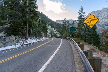 Foto de Señal de advertencia a lo largo de un sinuoso camino de montaña al atardecer en otoño. Lake Tahoe, CA, Estados Unidos. - Imagen libre de derechos