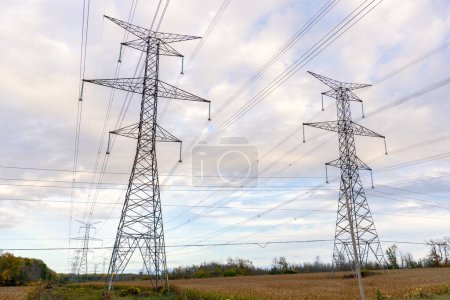 Foto de Pilones de acero altos que soportan líneas de alto voltaje sobre tierras de cultivo en un día nublado de otoño. Ontario, Canadá. - Imagen libre de derechos