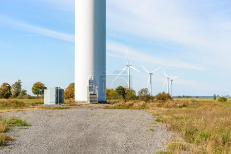 Foto de Puerta en la base de una torre que sostiene un aerogenerador en un parque eólico en el campo en un día soleado de otoño. Otras turbinas eólicas son visibles en el fondo. Wolfe Island, ON, Canadá. - Imagen libre de derechos