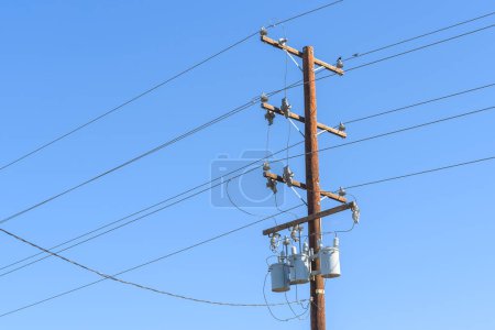 Foto de Detalle de un poste eléctrico de madera que soporta cables y transformadores de voltaje hing contra el cielo azul. California, Estados Unidos. - Imagen libre de derechos