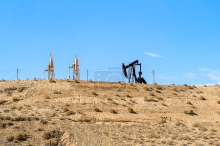 Photo for Pumjacks for oil extraction on the top of a desert hill on a clear autumn day. Bakersfield, CA, USA. - Royalty Free Image