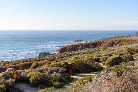 Téléchargez les photos : Corbeille de recyclage le long d'un sentier abandonné sur la côte californienne par une journée ensoleillée d'automne. Carmel-by-the-Sea, CA, États-Unis. - en image libre de droit