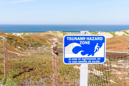 Photo for Close up of tsunami warning sign along a path through coastal sand dunes on a sunny autumn day. Marina, CA, USA - Royalty Free Image