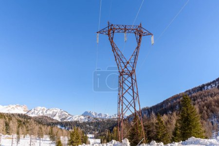 Téléchargez les photos : Grand pylône électrique dans un paysage de montagne enneigé par une journée d'hiver claire - en image libre de droit