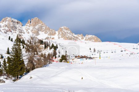 Téléchargez les photos : Pistes de ski avec remontées mécaniques au pied d'imposants sommets rocheux enneigés dans les dolomites par une journée d'hiver ensoleillée - en image libre de droit