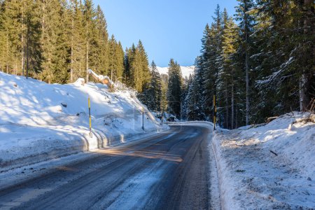 Foto de Camino helado aunque un nevado paso de montaña boscosa en un día claro de invierno - Imagen libre de derechos