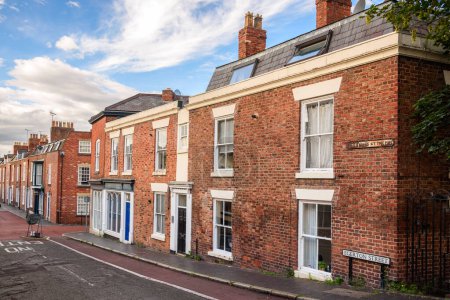 Foto de Fila de antiguas casas adosadas de ladrillo británico a lo largo de una calle bajo el cielo azul con nubes al atardecer. Chester, Inglaterra, Reino Unido. - Imagen libre de derechos