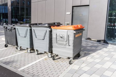 Téléchargez les photos : Rangée de poubelles usagées et de poubelles dans un parking à l'arrière d'un immeuble de bureaux moderne. Chester, Angleterre, RU. - en image libre de droit