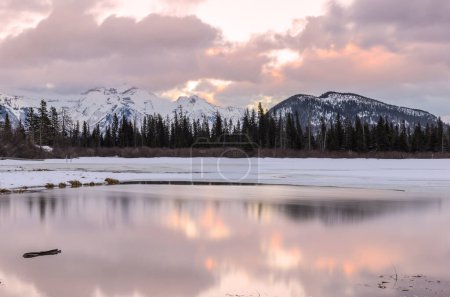 Téléchargez les photos : Lac de montagne gelé avec montagne enneigée en arrière-plan au coucher du soleil en hiver. Banff, AB, Canada. - en image libre de droit