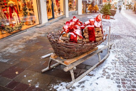 Photo for Christmas decorations on a old wooden sledge along a snowy cobbled street in a mountain village - Royalty Free Image