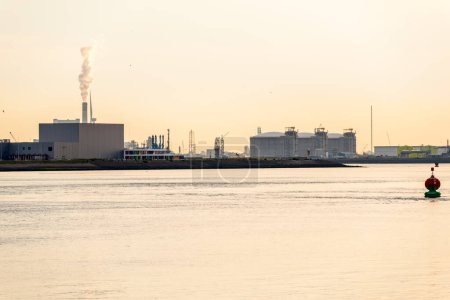Téléchargez les photos : Installations industrielles et réservoirs de stockage de carburant sur les quais d'un grand port maritime au coucher du soleil. Rotterdam, Pays-Bas. - en image libre de droit