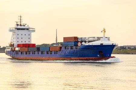 Téléchargez les photos : Navire porte-conteneurs entrant dans un port au coucher du soleil en été. Rotterdam, Pays-Bas. - en image libre de droit
