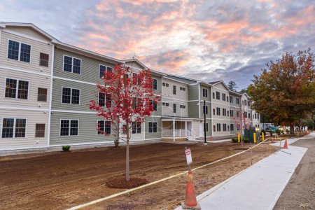 Foto de Exetrior de un edificio de apartamentos en construcción endesarrollo suburbano bajo cielo dramático al atardecer. Keene, NH, Estados Unidos. - Imagen libre de derechos