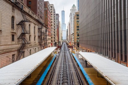 Téléchargez les photos : Station surélevée et voies ferrées du système de transport en commun rapdit Chicago entre des immeubles de grande hauteur dans le centre-ville par une journée nuageuse de printemps. Illinois, États-Unis. - en image libre de droit