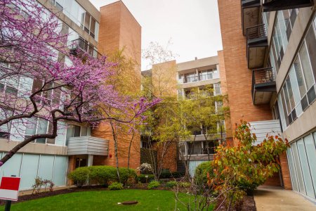 Téléchargez les photos : Vue à angle bas d'un immeuble moderne avec un petit jardin commun par une journée nuageuse de printemps. Chicago, IL, États-Unis. - en image libre de droit