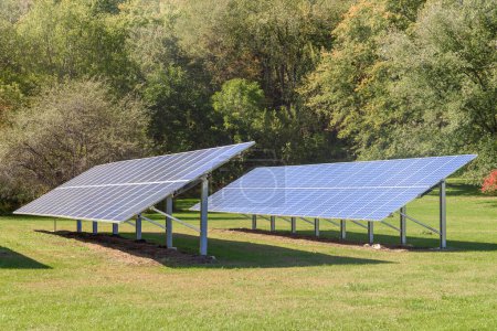 Filas de paneles solares en un jardín rodeado de árboles en un día soleado de otoño. Catskill Mountains, NY, Estados Unidos.