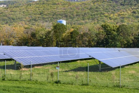 Planta de energía solar con hileras de paneles solares en un paisaje de montaña boscosa en otoño. Catskill Mountains, NY, Estados Unidos.