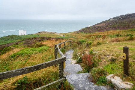 Schmaler eingezäunter Pfad mit Stufen, der an einem nebligen Sommertag zu einem Aussichtspunkt auf einem Leuchtturm an der Küste von Nordwales führt. South Stack Lighthouse, Holyhead, Anglesey, Wales, Großbritannien.