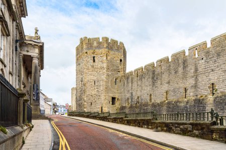 Rue déserte le long des murs d'un château historique et à travers la vieille ville du Pays de Galles. Caernarfon, Pays de Galles, Royaume-Uni.