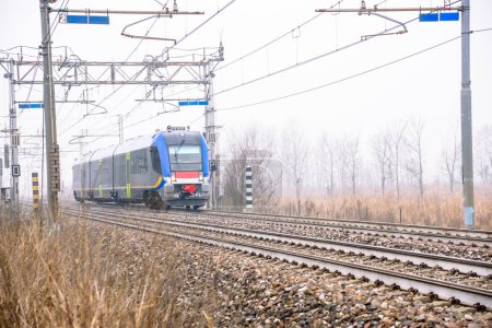 Téléchargez les photos : Train de voyageurs diesel traversant la campagne par une journée d'hiver brumeuse - en image libre de droit