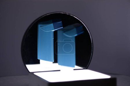 Foto de Inhalador de salbutamol que se utiliza para el tratamiento del asma, frente a un espejo con una imagen de espejo enfocada. - Imagen libre de derechos