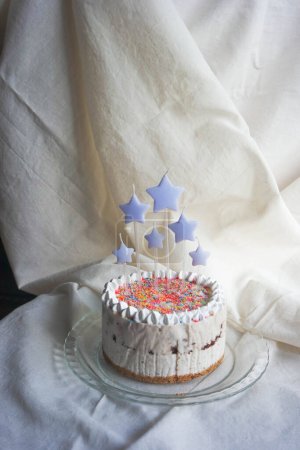 Foto de Tarta de cumpleaños con velas lindas hechas de helado de plátano, brownies, galletas y espolvoreos en fondo de tela blanca - Imagen libre de derechos