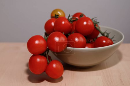 Foto de Tomates rojos frescos en una caja de platos sobre una mesa de madera - Imagen libre de derechos