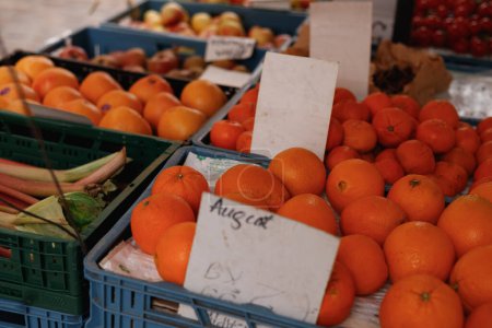 Various fruits, oranges in boxes on market counters.
