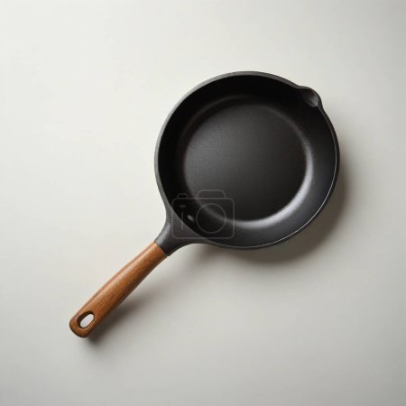 Top view of a new, empty cast iron pan with wooden handle isolated on a light background