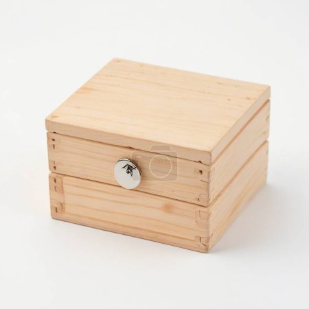 Caja de madera de pino simplista con una pequeña perilla de plata sobre un fondo blanco limpio