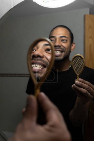 Téléchargez les photos : Latino homme avec une dent cassée se regardant dans le miroir - en image libre de droit