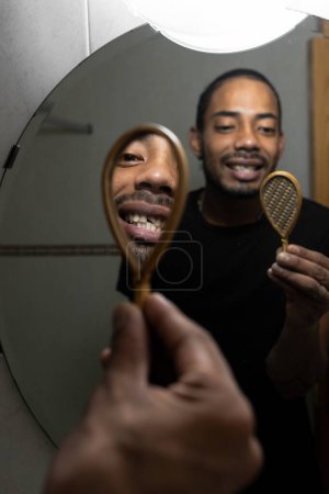 Téléchargez les photos : Latin homme qui vient de se casser la dent et est dans la salle de bain en se regardant dans le miroir. - en image libre de droit