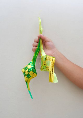 Photo for A child hand holding traditional ketupat, made from yellow and green ribbon - Royalty Free Image