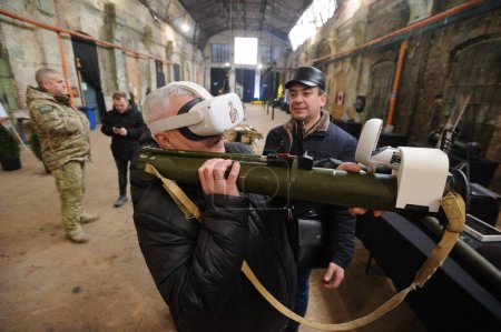 Photo for Lviv, Ukraine 23 December 2022.  Ukrainian serviceman shows a civilian how to operate an anti-tank weapon during the Weapon of Victory exhibition. Russia invaded Ukraine on 24 February 2022, triggering the largest military attack in Europe since Worl - Royalty Free Image