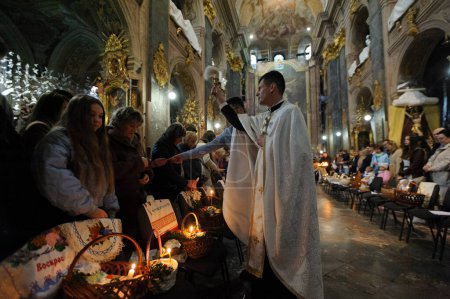 Photo for Lviv, Ukraine 15 April 2023. A Ukrainian priest blesses believers at a Greek Catholic church of Saints Peter and Paul Garrison Church as they celebrate Easter to mark the resurrection of Jesus Christ from the dead and the foundation of the Christian - Royalty Free Image