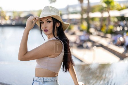Foto de Joven mujer caucásica con los ojos claros en vacaciones posando para una foto con su sombrero mirando a la cámara - Imagen libre de derechos