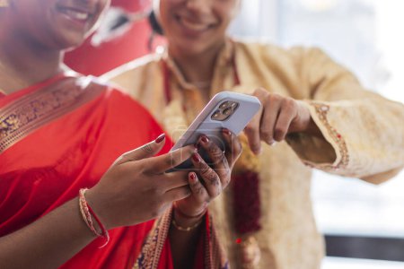 Téléchargez les photos : Gros plan du couple indien en utilisant mobile. ses mains ont des dessins au henné - en image libre de droit