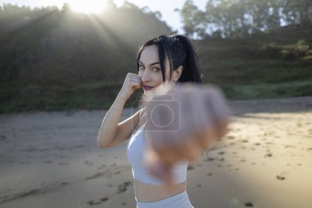 Photo for Young adult female runner is boxing on the beach after a long run at sunrise - Royalty Free Image