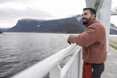 Téléchargez les photos : Jeune homme appuyé sur la rampe sur le bateau pendant les vacances - en image libre de droit