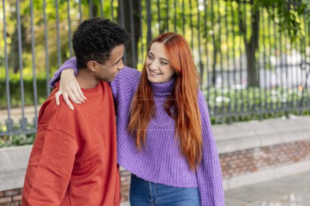 Photo for Friends meeting again on the street. Redhead friend hugs her African American boy friend - Royalty Free Image