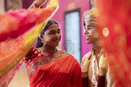 Téléchargez les photos : Cérémonie hindoue célébrant le mariage avec des écharpes près de la caméra, le jeune couple se regarde dans les yeux - en image libre de droit