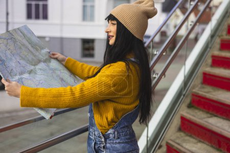 Foto de Turista mujer planea su viaje, tiene un mapa en papel para elegir la próxima dirección de su aventura - Imagen libre de derechos