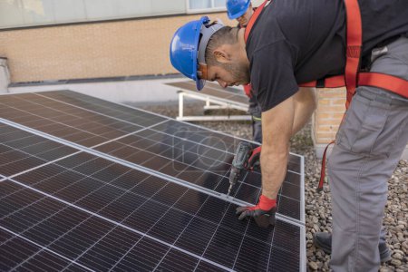 Foto de Primer plano del trabajador instalando un panel solar en una azotea con su herramienta - Imagen libre de derechos
