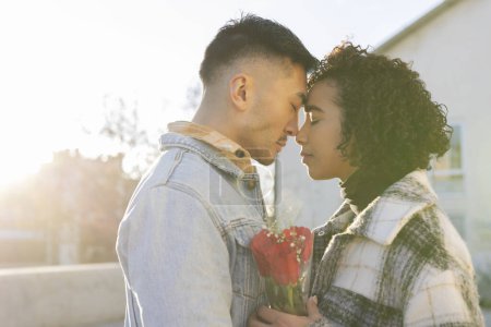 Téléchargez les photos : Portrait d'amoureux multiraciaux les yeux fermés et la tête avec contre-jour au coucher du soleil et un bouquet de roses à la main - concept de Saint-Valentin - en image libre de droit