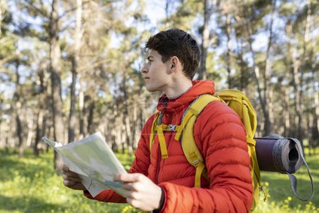 Téléchargez les photos : Jeune homme adulte randonneur dans la forêt avec sa carte - en image libre de droit