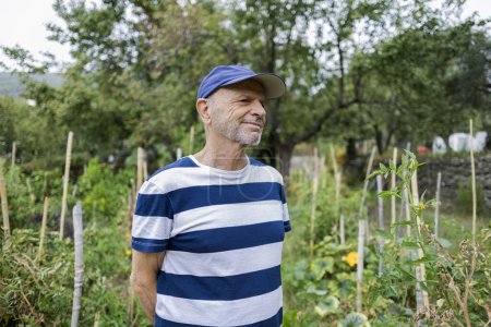 Téléchargez les photos : Portrait d'un agriculteur âgé fier de ses progrès dans son jardin dont il s'occupe après sa retraite - en image libre de droit
