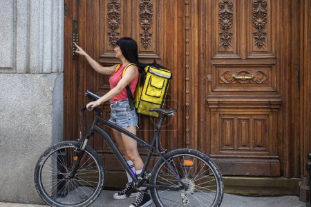 Foto de Entrega mujer tocando el timbre con su bicicleta - Imagen libre de derechos