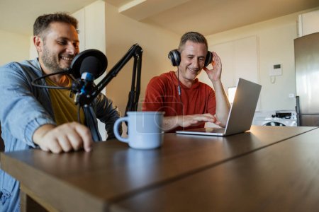 Téléchargez les photos : Hommes enregistrement podcast en direct avec écouteurs, microphone et ordinateur portable - en image libre de droit