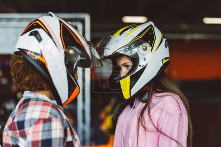 Adolescentes rivales colocando cascos juntos mirándose a los ojos antes del campeonato de karts