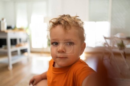 Photo for Little boy taking a selfie at home with the phone portrait looking at the camera - Royalty Free Image